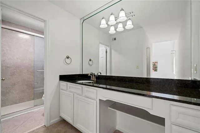 a bathroom with a granite countertop sink a large mirror and a shower