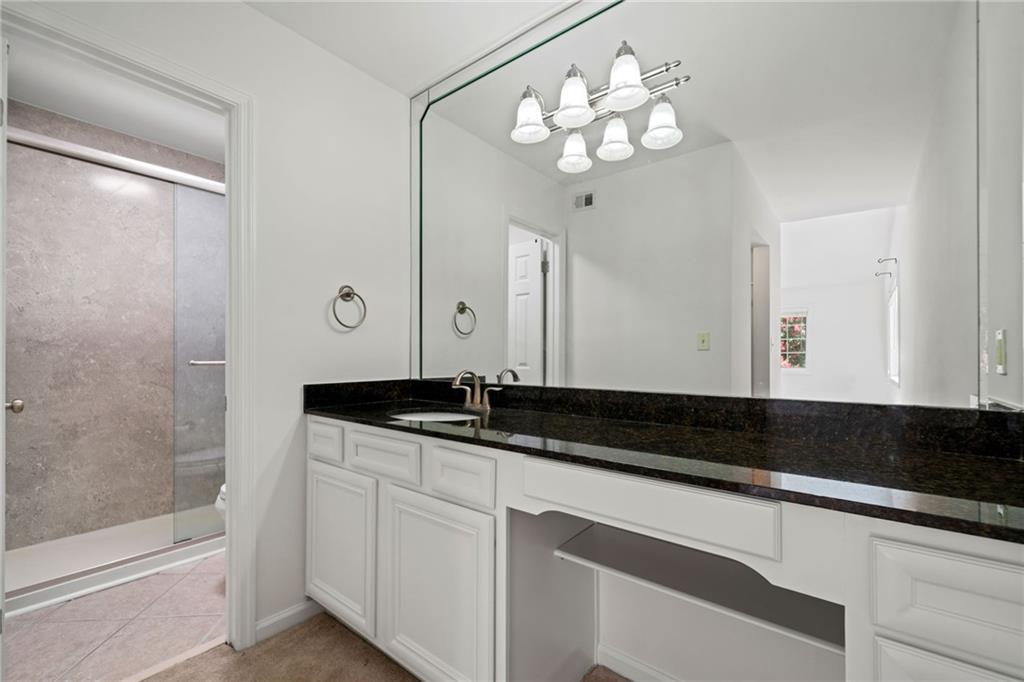 1468 Briarwood Road Northeast, Unit 108 Atlanta, GA 30319 - Photo 17 of 33 a bathroom with a granite countertop sink a large mirror and a shower
