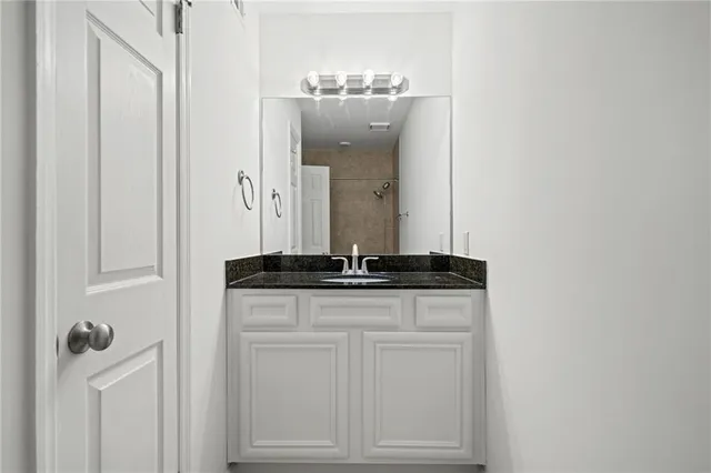 a bathroom with a granite countertop sink and a mirror