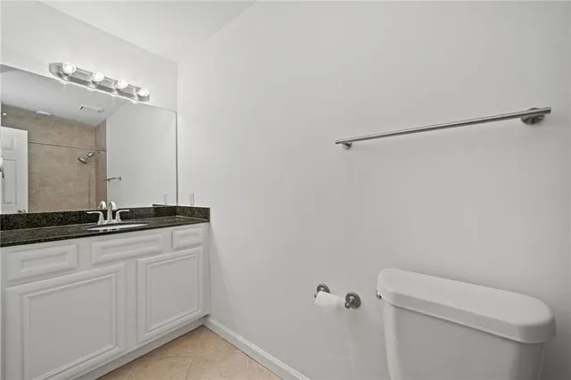 a bathroom with a granite countertop sink a toilet and a mirror