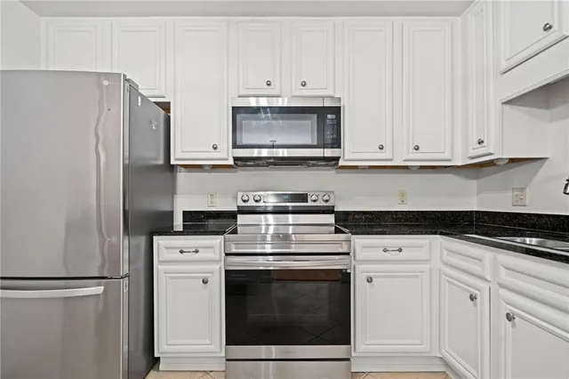 a kitchen with granite countertop white cabinets and stainless steel appliances