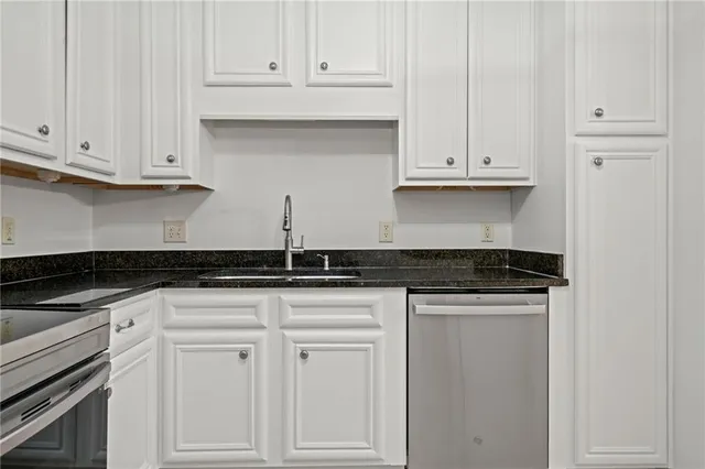 a kitchen with granite countertop white cabinets and a stove