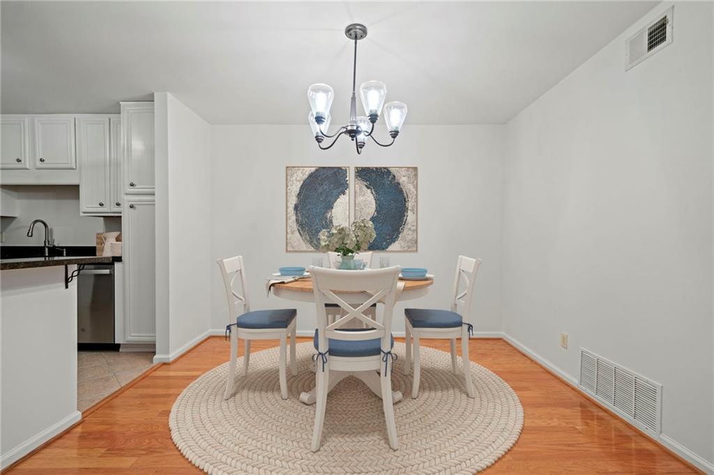 1468 Briarwood Road Northeast, Unit 108 Atlanta, GA 30319 - Photo 9 of 33 a dining room with wooden floor a chandelier a wooden table and chairs