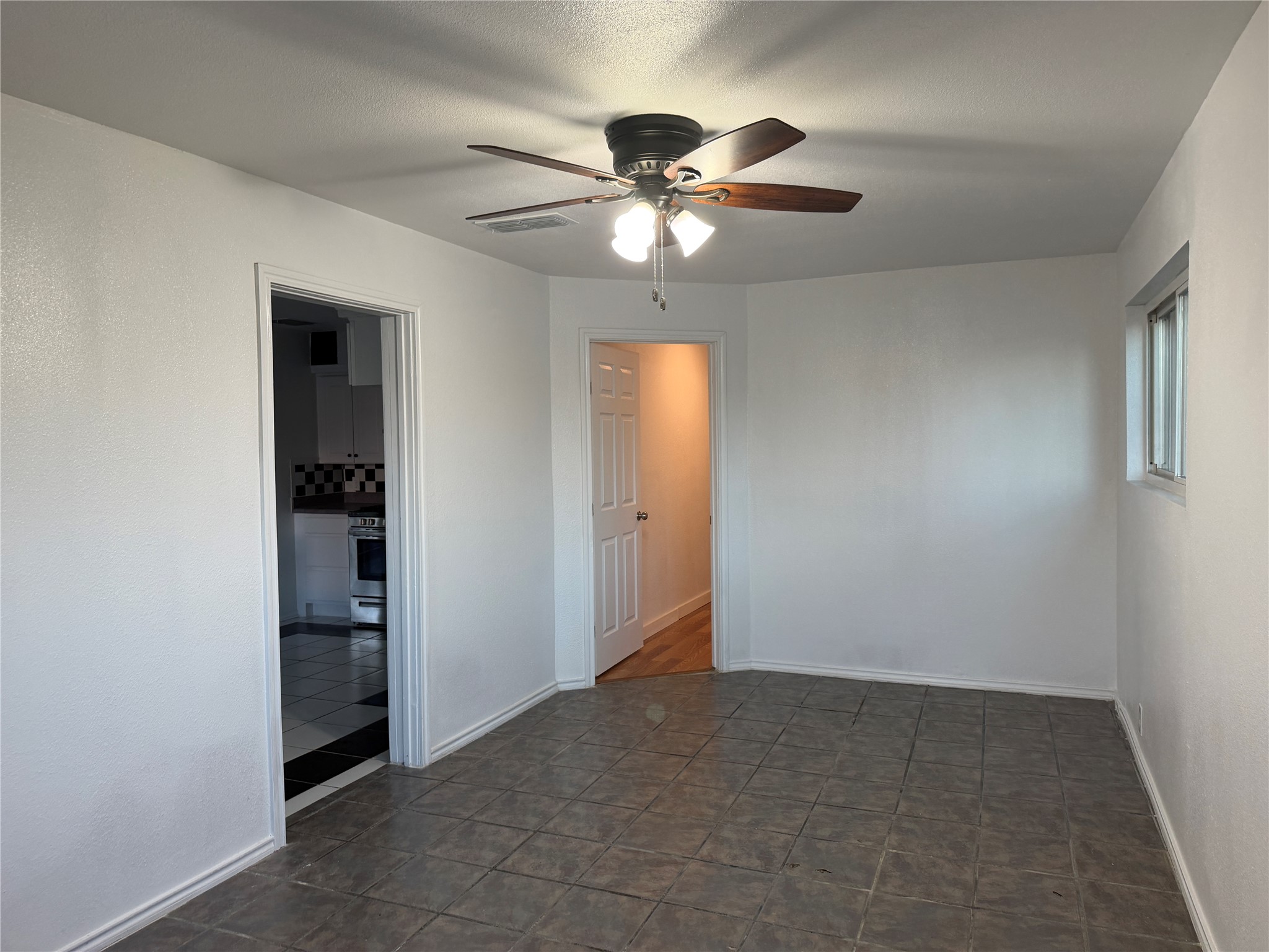 1060 Gardner Road Austin, TX 78721 - Photo 9 of 19 A well-lit interior space with tiled floors and a ceiling fan, offering a clean, adaptable layout.