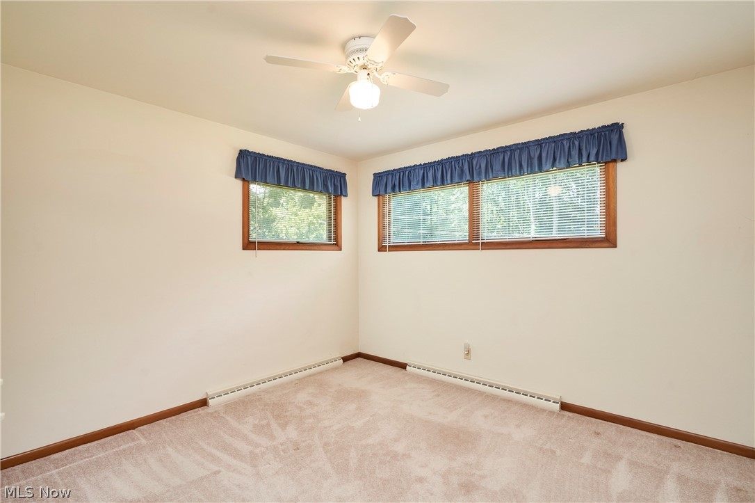 299 West Caston Road New Franklin, OH 44319 - Photo 15 of 23 Carpeted interior space featuring two windows with wood frames and blinds, baseboard heating, and a ceiling fan with integrated lighting