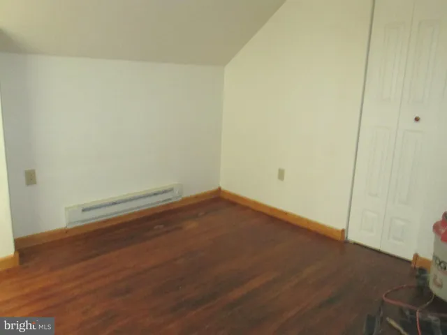 an empty room with wooden floor and mirror