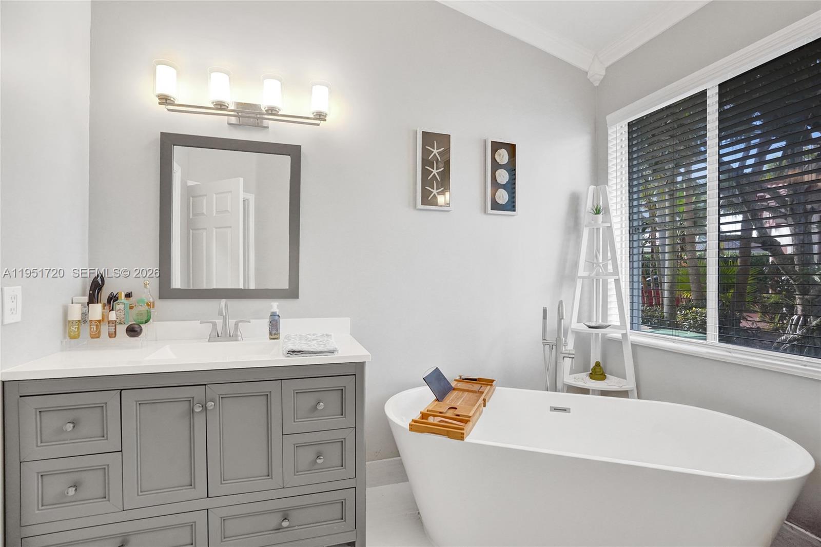 8795 Northwest 76th Place Tamarac, FL 33321 - Photo 20 of 69 a bathroom with a bathtub a sink a mirror and a window