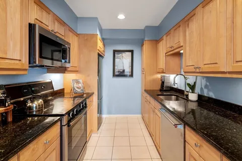 a kitchen with granite countertop a stove top oven microwave and cabinets