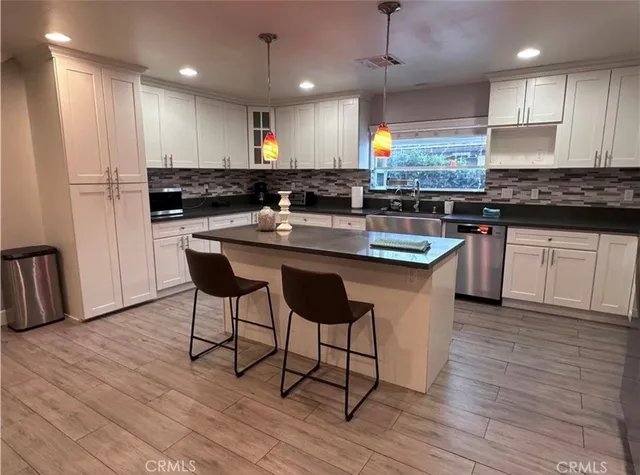 a kitchen with stainless steel appliances granite countertop a table chairs sink refrigerator and microwave
