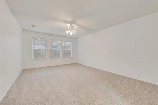 a view of an empty room with a ceiling fan and a window