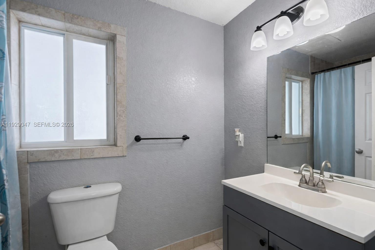 3109 Northwest 64th Street Miami, FL 33147 - Photo 18 of 20 a bathroom with a toilet a sink a mirror and a window