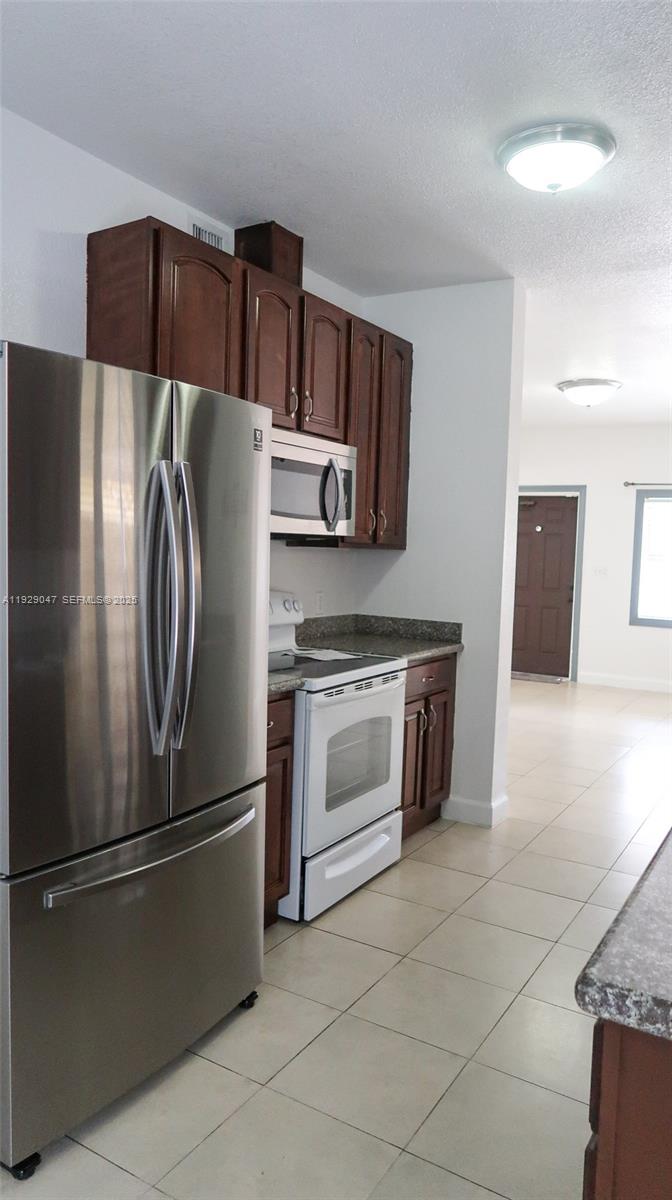 3109 Northwest 64th Street Miami, FL 33147 - Photo 28 of 38 a kitchen with stainless steel appliances granite countertop a refrigerator and a stove top oven