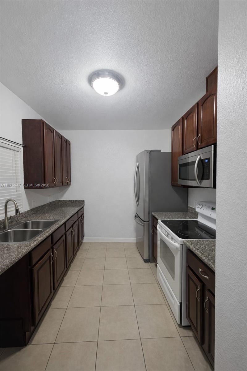 3109 Northwest 64th Street Miami, FL 33147 - Photo 6 of 20 a kitchen with stainless steel appliances granite countertop a stove top oven a sink and dishwasher a refrigerator with wooden cabinets