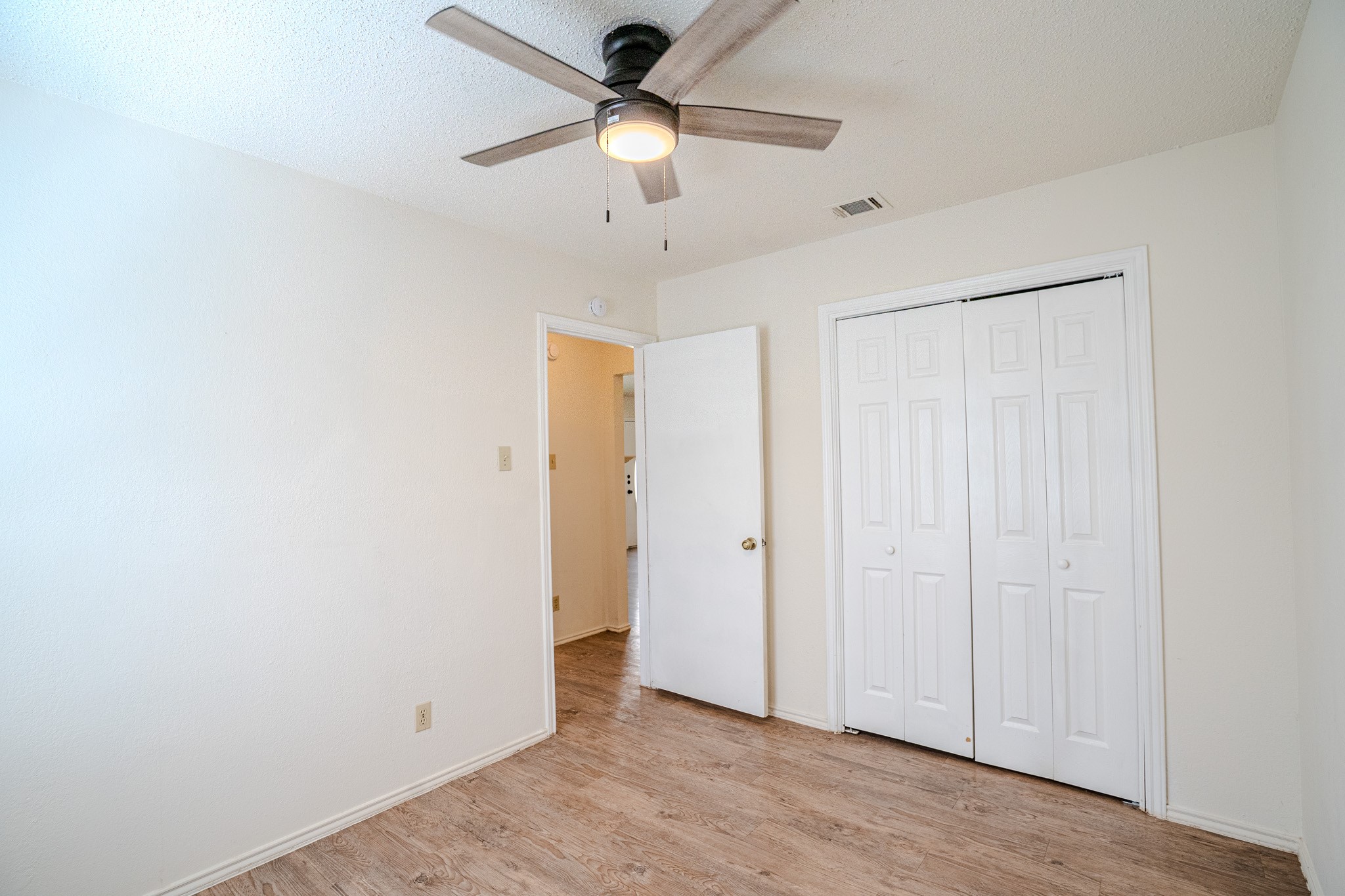 517 Cutty Trail, Unit B Lakeway, TX 78734 - Photo 10 of 16 A well-lit bedroom with laminate flooring and a functional ceiling fan.