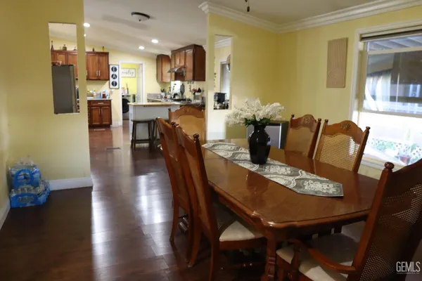 a dining room with furniture wooden floor a rug and a kitchen view