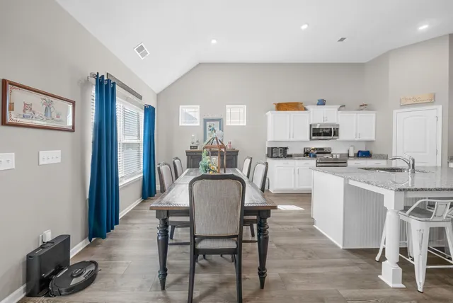 a dining room with kitchen island stainless steel appliances a table and chairs in it