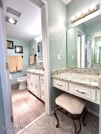 a bathroom with a granite countertop sink a toilet and a mirror