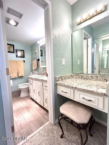 a bathroom with a granite countertop sink a toilet and a mirror