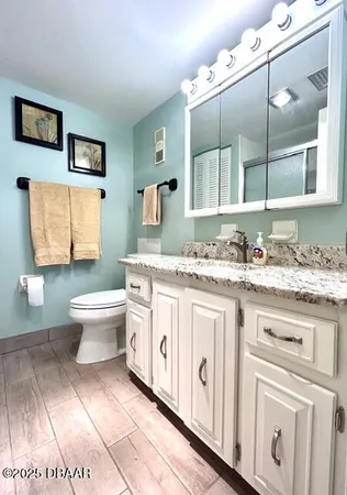 a bathroom with a granite countertop toilet sink and mirror