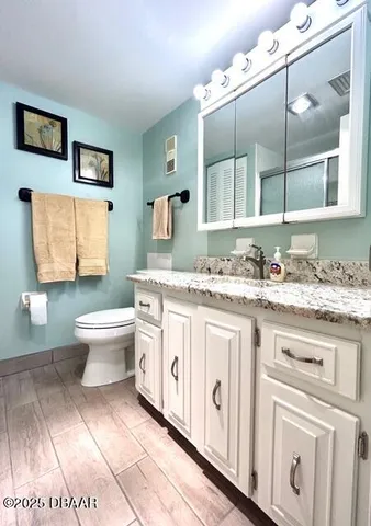 a bathroom with a granite countertop toilet sink and mirror