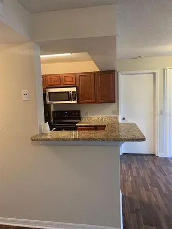 a kitchen with kitchen island granite countertop a stove a sink and a microwave