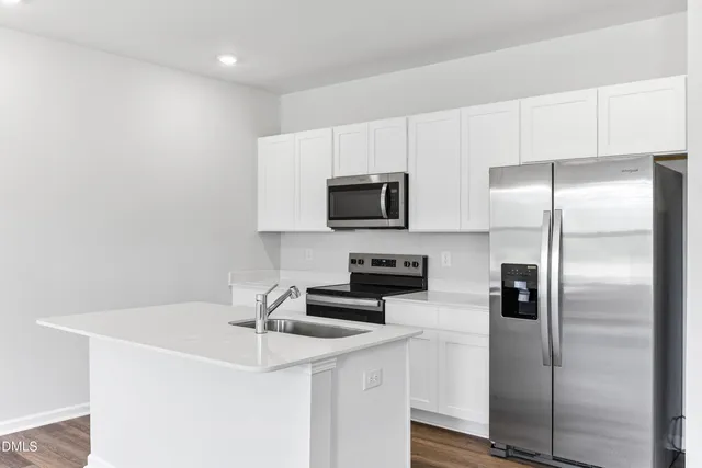 a kitchen with a refrigerator a microwave a sink and cabinets