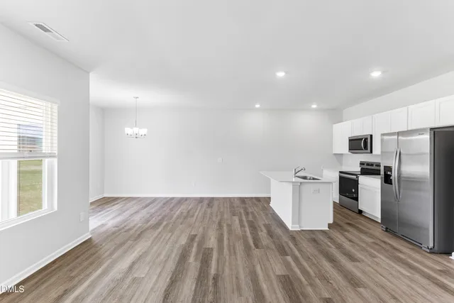 a kitchen with stainless steel appliances a sink a stove a refrigerator with white cabinets