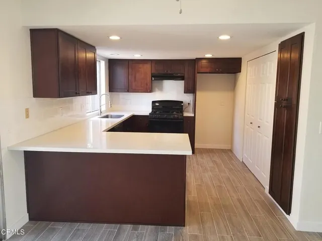 a kitchen with stainless steel appliances granite countertop a refrigerator a sink a stove a microwave and wooden floor