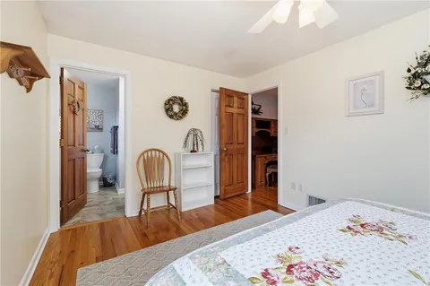a bedroom with a bed and a dresser with the wooden floor