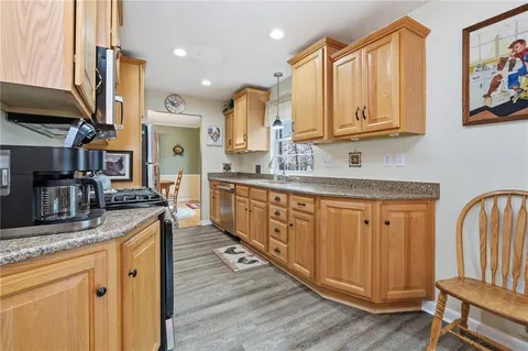 a kitchen with stainless steel appliances granite countertop a sink dishwasher stove and wooden cabinets with wooden floor