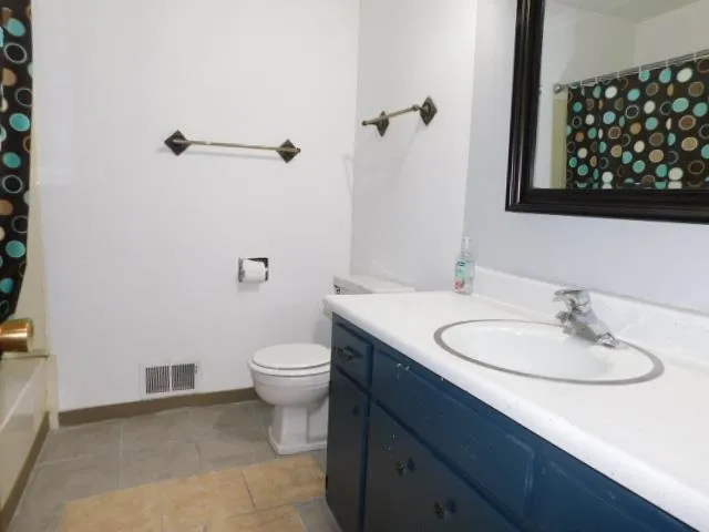 a bathroom with a granite countertop sink toilet and mirror