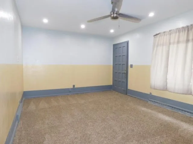 an empty room with a ceiling fan and window