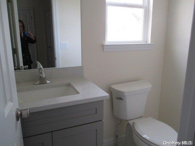 655 Bourdois Avenue Bellport, NY 11713 - Photo 12 of 28 a bathroom with a toilet a sink a window and mirror