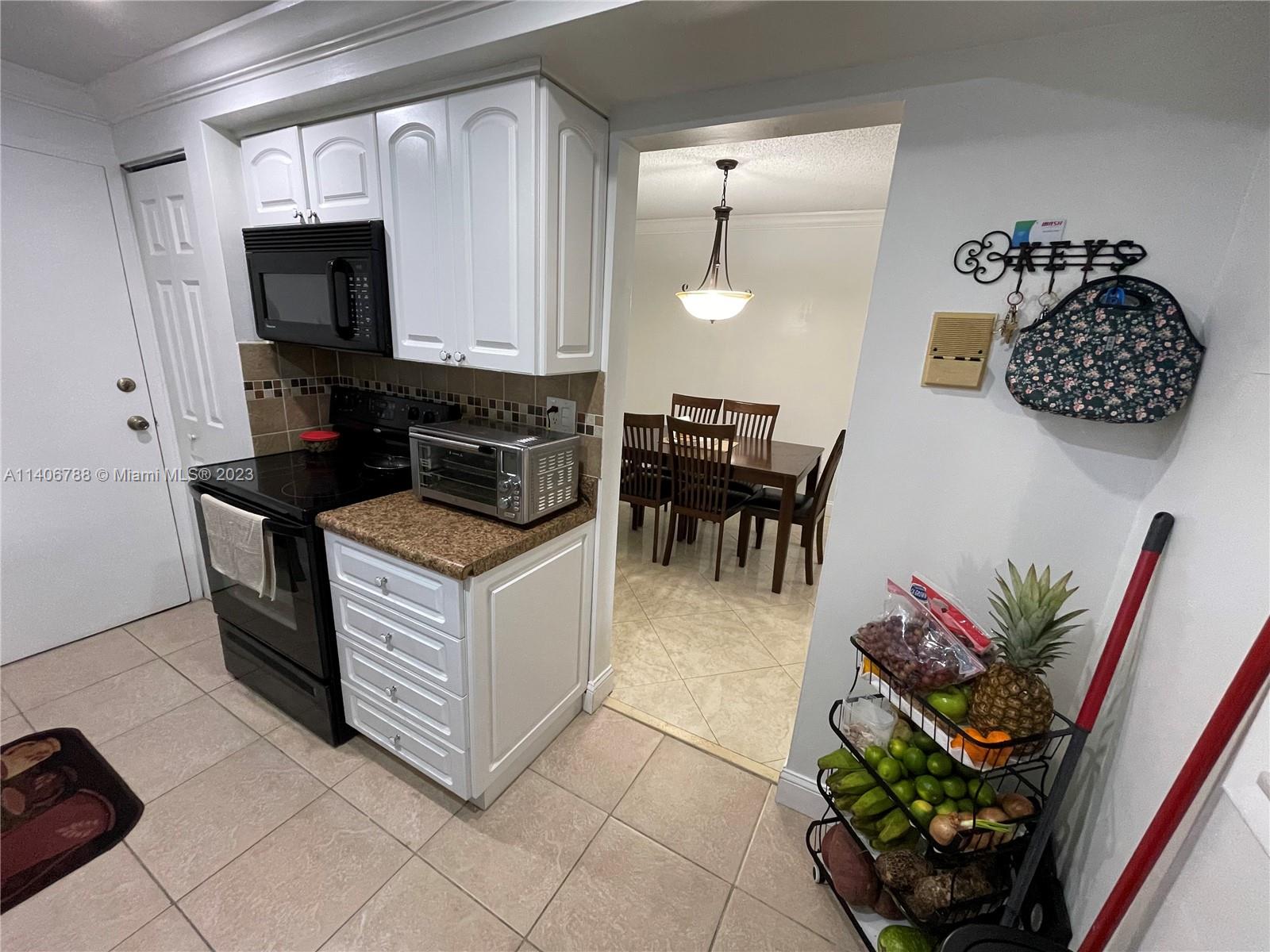 6861 Southwest 147th Avenue, Unit 2G Miami, FL 33193 - Photo 11 of 34 a kitchen with stainless steel appliances kitchen island granite countertop a stove a sink and a microwave
