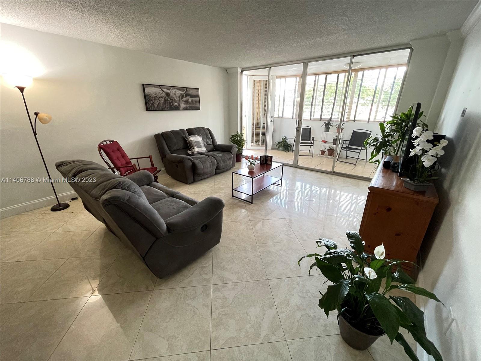 6861 Southwest 147th Avenue, Unit 2G Miami, FL 33193 - Photo 25 of 34 a living room with furniture floor to ceiling window and a potted plant
