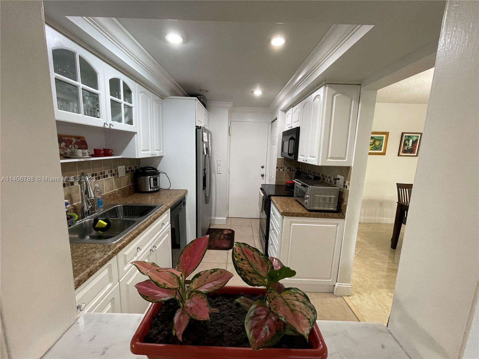 6861 Southwest 147th Avenue, Unit 2G Miami, FL 33193 - Photo 8 of 34 a kitchen with stainless steel appliances kitchen island granite countertop a refrigerator a stove and a sink with wooden floor