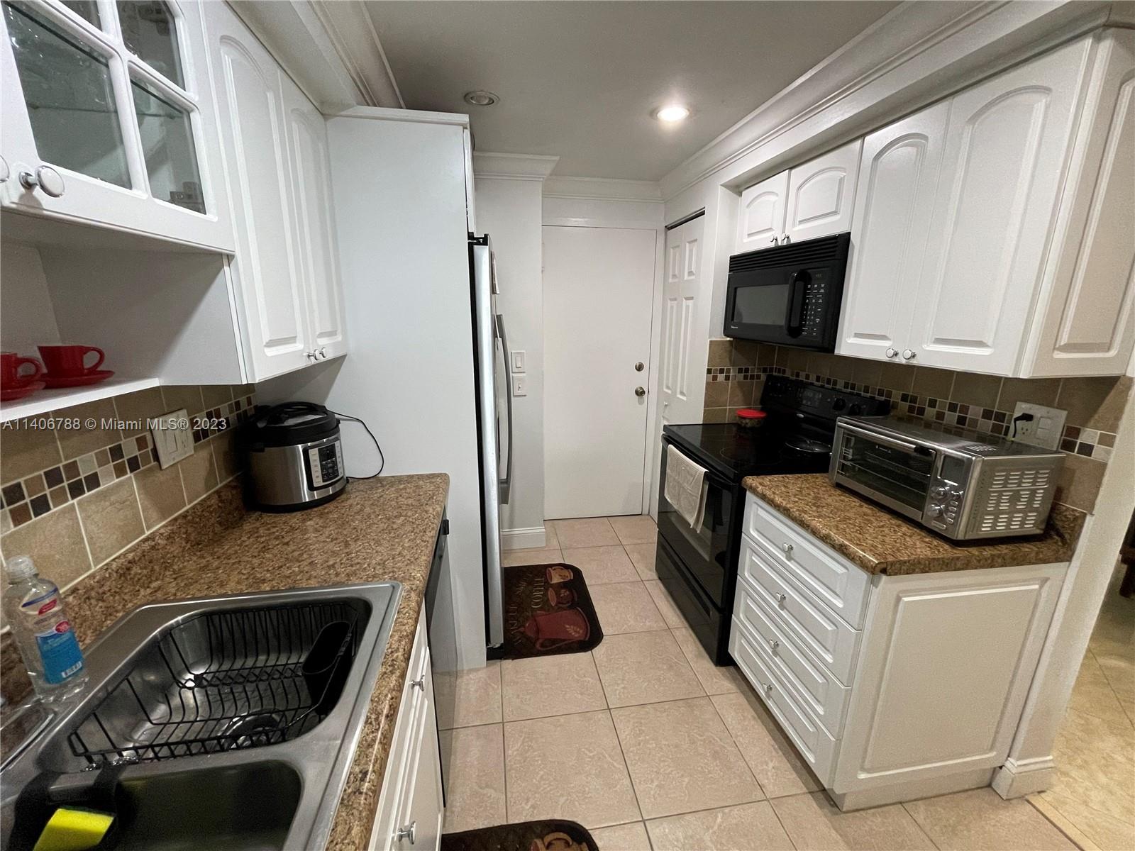 6861 Southwest 147th Avenue, Unit 2G Miami, FL 33193 - Photo 10 of 34 a kitchen with granite countertop a sink and a stove top oven