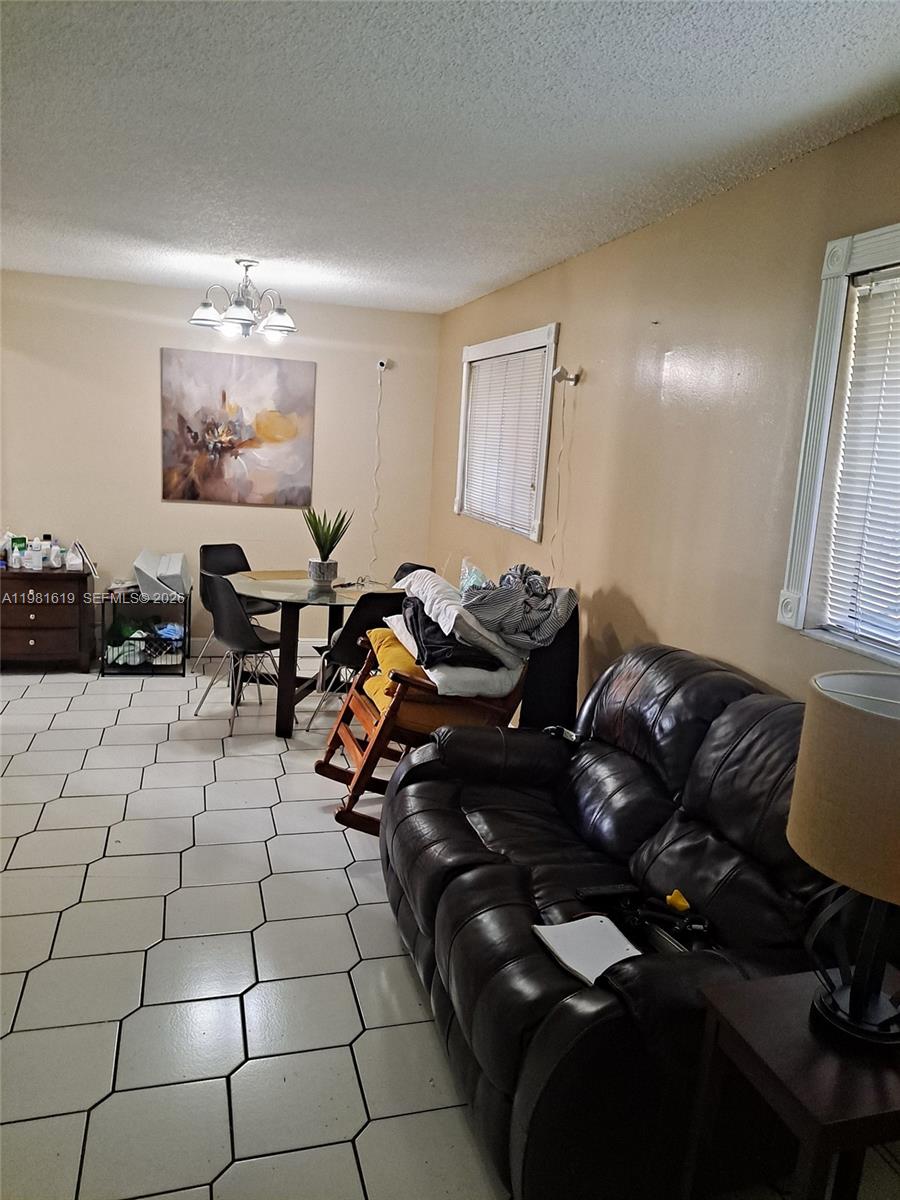 10765 Southwest 4th Street, Unit 1 Sweetwater, FL 33174 - Photo 3 of 6 a living room with furniture and a chandelier
