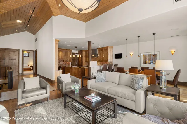 a living room with furniture kitchen view and a chandelier