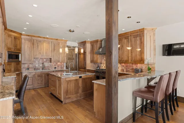 a kitchen with stainless steel appliances granite countertop a stove top oven a sink a dining table and chairs