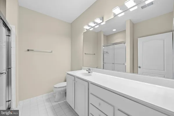 a bathroom with a sink a toilet a large mirror and vanity