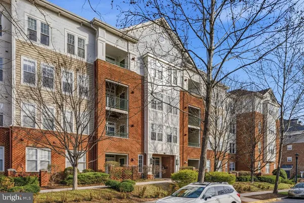 a front view of a building with lot of cars and trees