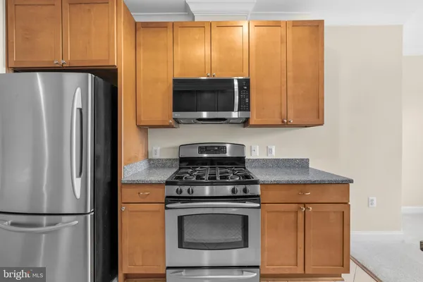 a kitchen with stainless steel appliances granite countertop a stove a refrigerator and a microwave oven with wooden cabinets