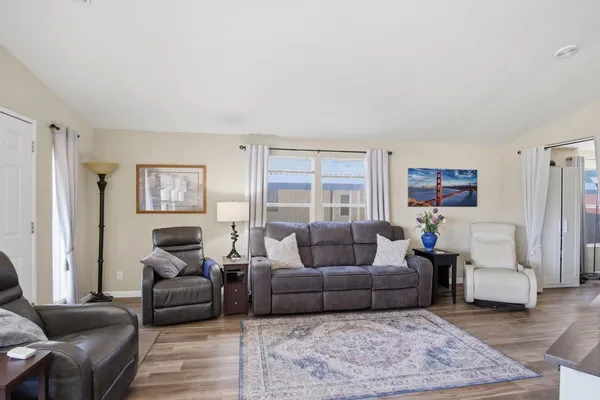 a living room with furniture potted plant wooden floor and a flat screen tv