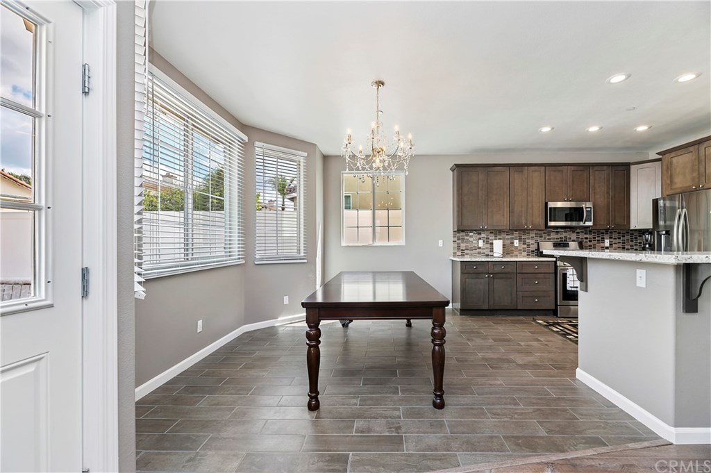 3591 Tyco Drive Riverside, CA 92501 - Photo 12 of 30 a kitchen with a refrigerator a sink dishwasher a stove and a dining table with wooden floor