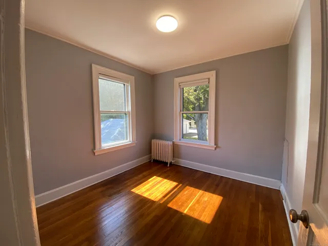 a view of empty room with a window and wooden floor