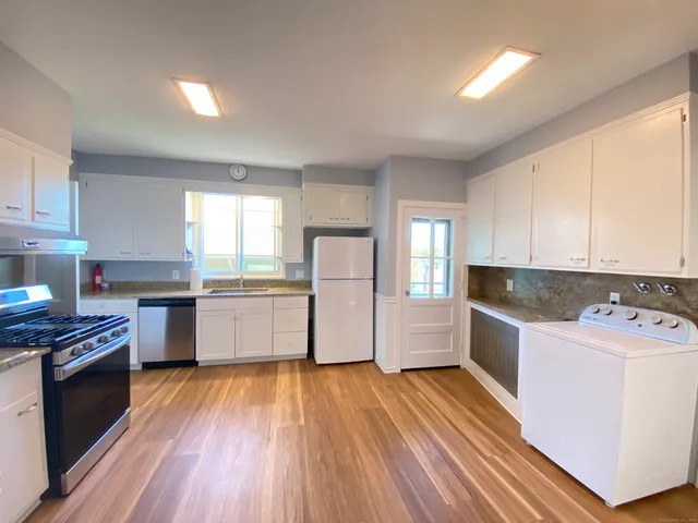 a kitchen with a sink wooden floor and stainless steel appliances