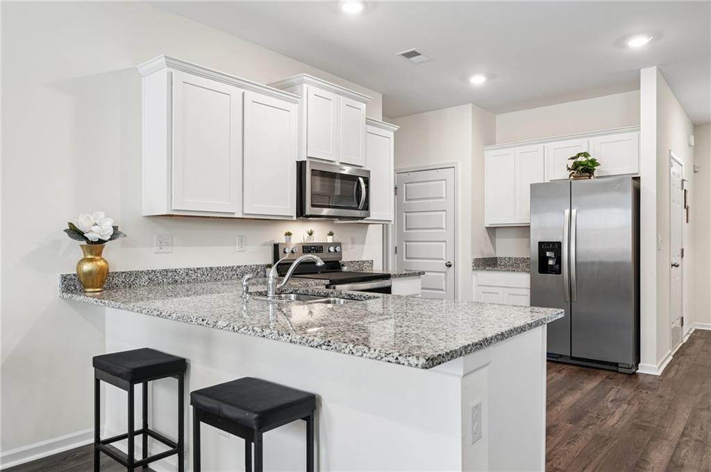 8592 Seabiscuit Road Lithonia, GA 30058 - Photo 5 of 25 a kitchen with kitchen island granite countertop a sink appliances and cabinets