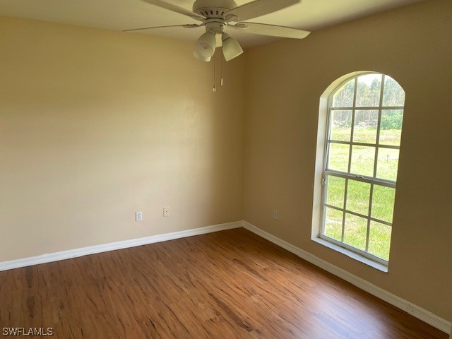 247 Rue Labonne Road Fort Myers, FL 33913 - Photo 5 of 14 an empty room with wooden floor fan and windows