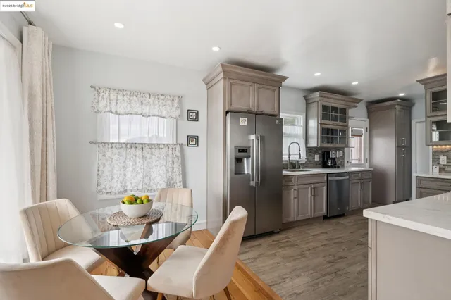 a kitchen with stainless steel appliances a refrigerator a sink a stove a dining table and chairs